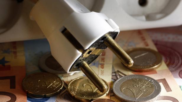 Ein Stecker liegt auf Euro-Banknoten und Münzen.