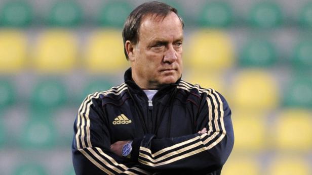 Ein Mann mit verschränkten Armen vor einem unscharfen Hintergrund.