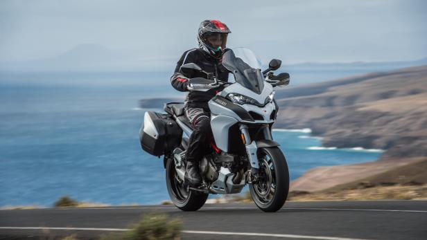 Ein Motorradfahrer fährt auf einer Ducati die Küstenstraße entlang.