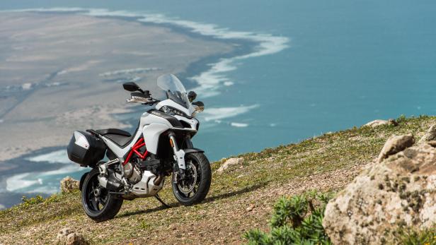 Eine weiße Ducati Multistrada steht auf einem Hügel mit Blick auf das Meer.