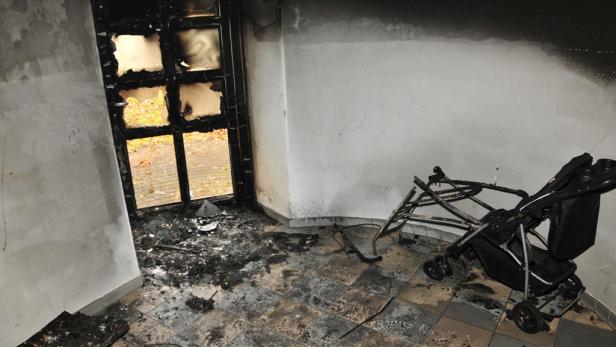Ein Kinderwagen steht in einem Raum, der durch ein Feuer beschädigt wurde.