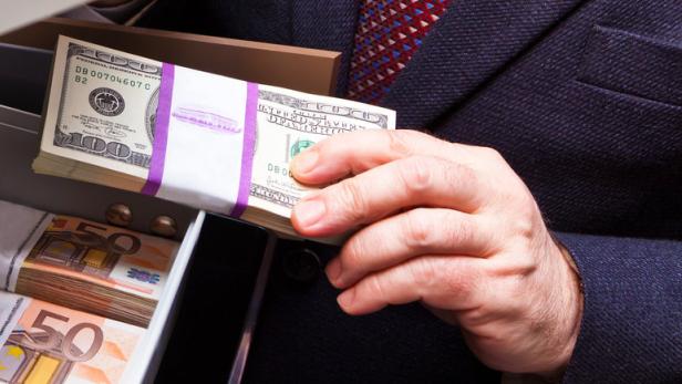 Eine Person öffnet einen Safe mit Bündeln von Dollar- und Euroscheinen.