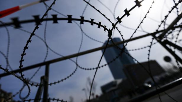 Stacheldraht vor einem Hochhaus unter einem hellen Himmel.