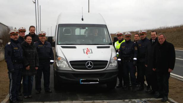 Eine Gruppe Polizisten posiert vor einem Einsatzfahrzeug.