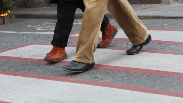 Zwei Personen überqueren einen Zebrastreifen.