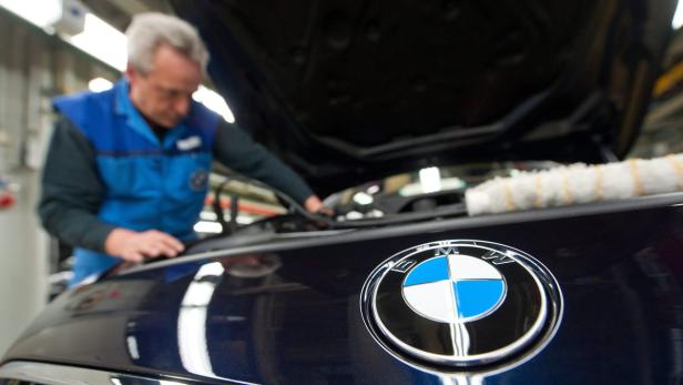 Ein Mechaniker arbeitet an einem BMW mit geöffneter Motorhaube.