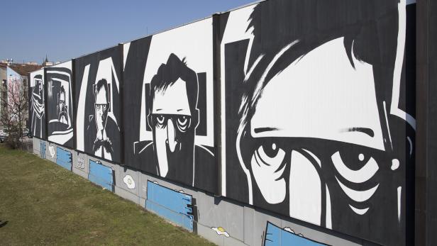 Eine große Wandmalerei zeigt stilisierte Porträts in Schwarz und Weiß.