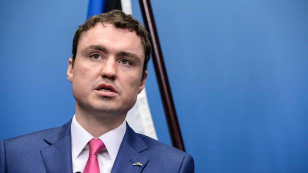 Ein Mann im Anzug vor einem blauen Hintergrund.