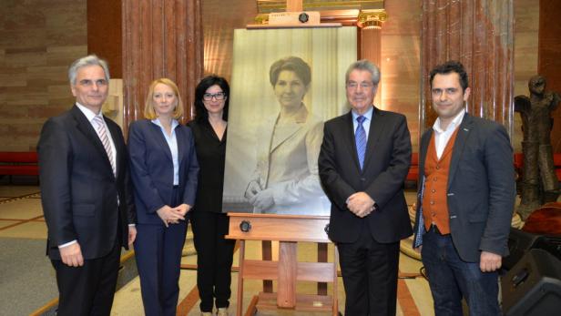 Fünf Personen posieren vor einem Porträtgemälde einer Frau.