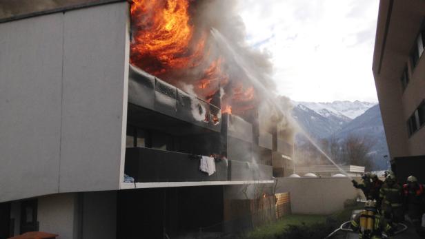 Ein brennendes Gebäude wird von Feuerwehrleuten mit Wasser bespritzt.