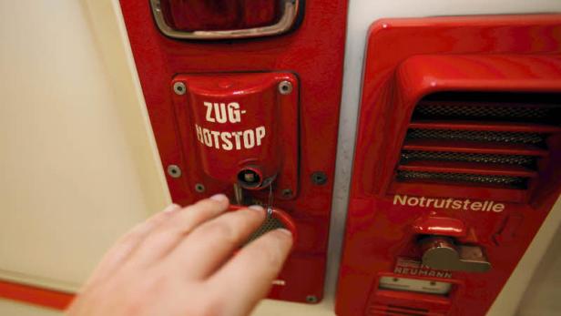 Eine Hand betätigt den Notstopp-Hebel in einem Zug.