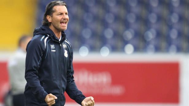 Ein Fußballtrainer gestikuliert auf dem Spielfeld.