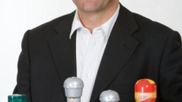 Ein Mann in einem Anzug posiert mit einer Auswahl an Kolányi-Gewürzen.