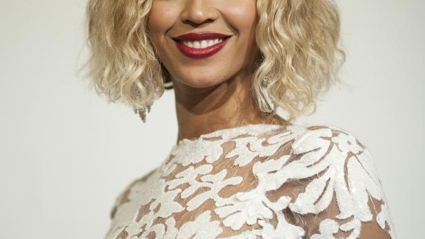 Beyoncé lächelt in einem weißen Spitzenkleid.