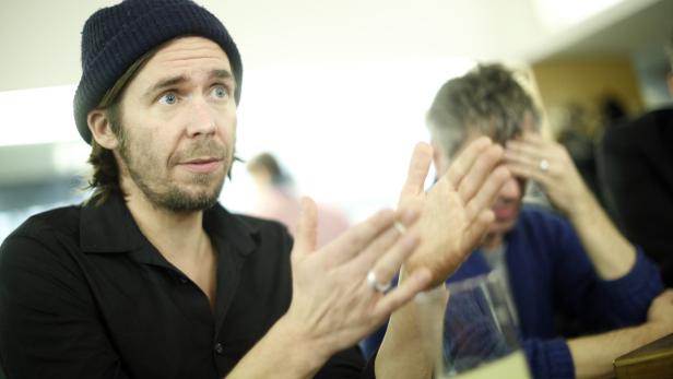 Ein Mann mit Mütze gestikuliert während eines Gesprächs.