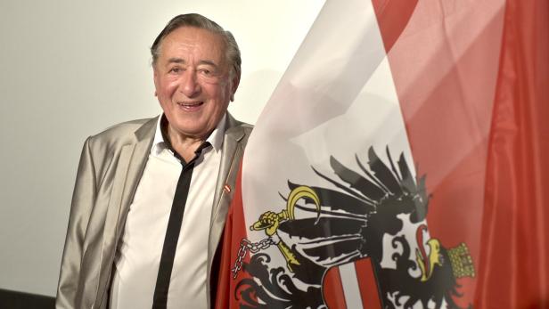 Ein lächelnder Mann posiert mit der österreichischen Flagge.