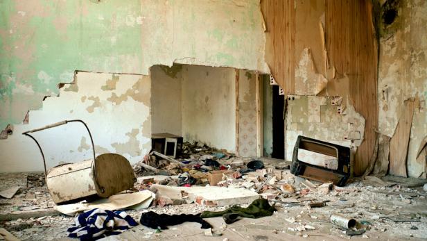Ein zerstörtes Zimmer mit Trümmern und beschädigten Möbeln.
