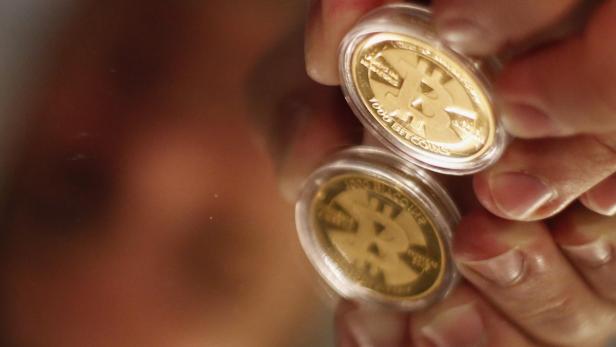 Eine Hand hält eine goldene Bitcoin-Münze in einer Schutzhülle.