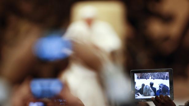 Menschen filmen eine Veranstaltung mit dem Papst auf ihren Tablets und Handys.