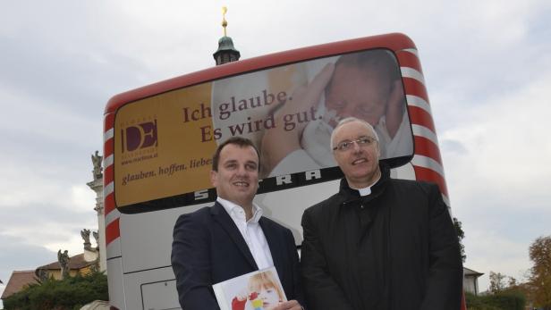 Zwei Männer stehen vor einem Bus der Diözese Eisenstadt mit dem Slogan „Ich glaube. Es wird gut.“.
