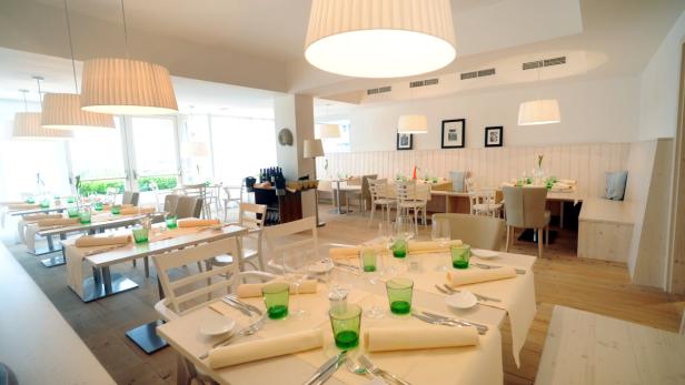 Ein helles Restaurant mit gedeckten Tischen und großen Lampen.