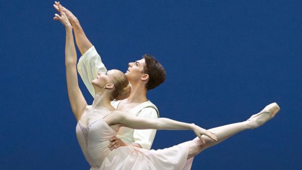 Ein Ballettpaar tanzt vor einem blauen Hintergrund.