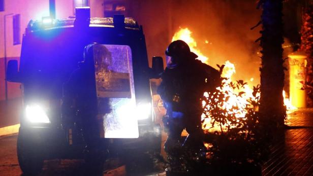 Polizisten stehen mit einem gepanzerten Fahrzeug vor einem Brand.