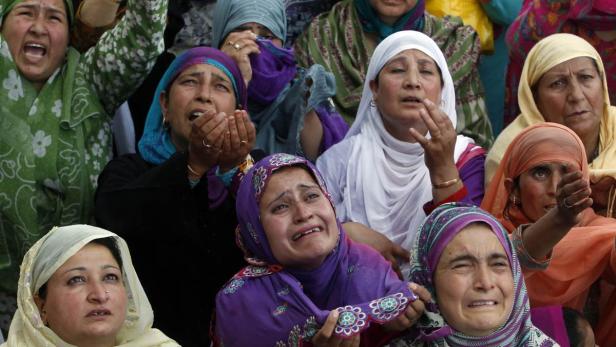 Eine Gruppe muslimischer Frauen weint und gestikuliert bei einer Versammlung.