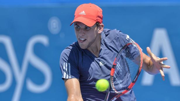 Ein Tennisspieler mit roter Kappe schlägt einen gelben Tennisball.