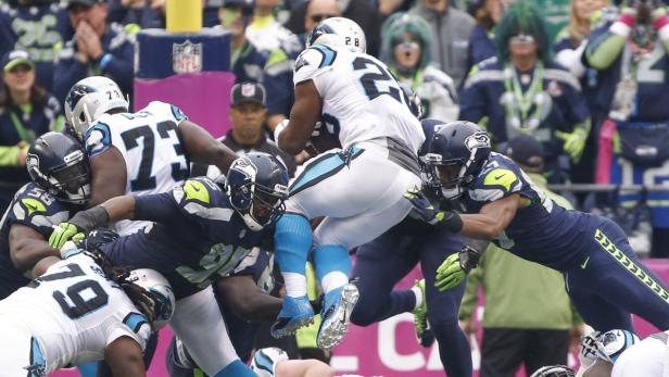 Ein Footballspieler springt über die Verteidigungslinie.