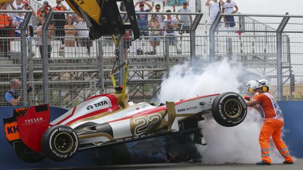 Ein Formel-1-Wagen wird nach einem Unfall von einem Kran geborgen, während Streckenposten helfen.