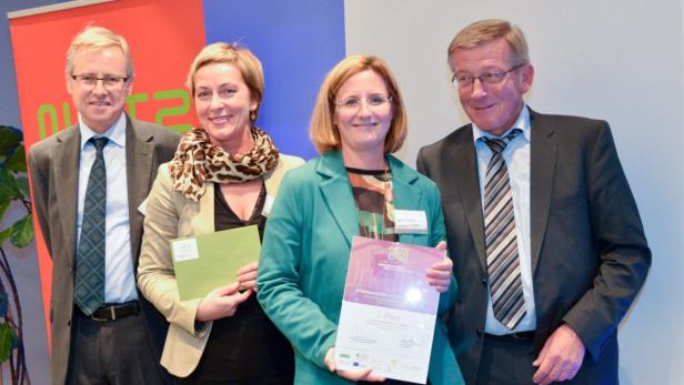 Vier Personen posieren mit Urkunden für ein Foto.