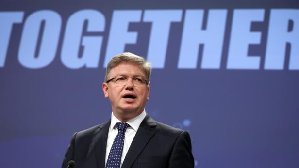 Ein Mann mit Brille und Anzug spricht vor einem Hintergrund mit dem Wort „Together“.