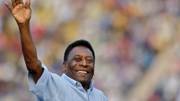Pelé lächelt und hebt die Hand vor einer Menschenmenge.