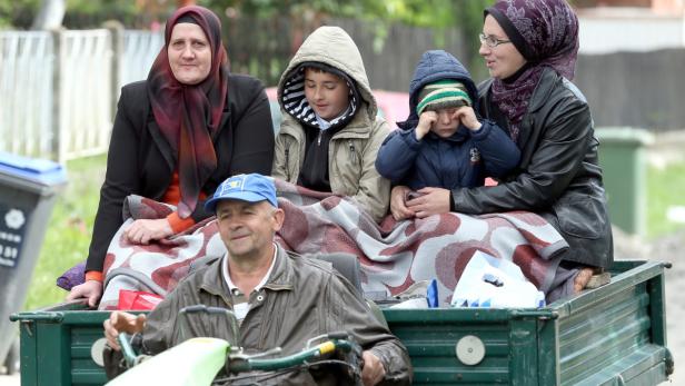 Eine Familie sitzt auf der Ladefläche eines kleinen Traktors, gehüllt in eine Decke.