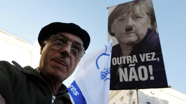 epa03468492 A protester holds a poster with the image of the German Chancellor Angela Merkel with the words &#039;Not Again!&#039; during a demonstration organized by the CGTP-IN union against the visit of German Chancellor Angela Merkel, in Lisbon, Portugal, 12 November 2012. German Chancellor Angela Merkel praised Portugal&#039;s austerity measures, saying they had improved conditions for future economic growth. &#039;I can feel a great determination to master this difficult phase,&#039; Merkel said after meeting Portuguese Prime Minister Pedro Passos Coelho in Lisbon. The current economic policies spelled hardship for the population, Merkel conceded, pledging German support to professional training programmes in Portugal. EPA/MANUEL DE ALMEIDA