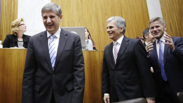 Mehrere Männer in Anzügen lachen und applaudieren in einem holzgetäfelten Raum.