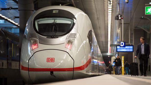 Ein ICE der Deutschen Bahn steht an einem Bahnsteig, ein Reisender geht vorbei.