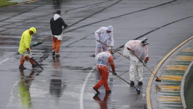 Marshals remove excess water on the track before t