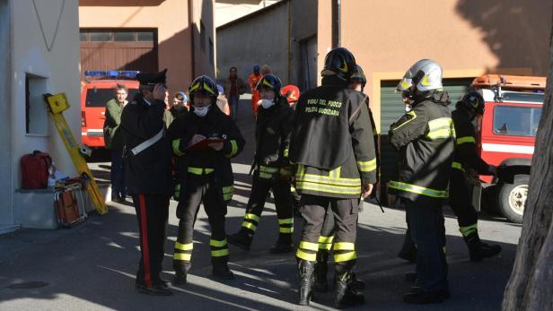 Eine Gruppe von Feuerwehrleuten und ein Polizist stehen auf einer Straße.