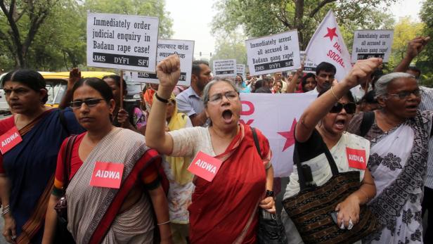 Frauen demonstrieren mit Schildern und erhobenen Fäusten gegen sexuelle Gewalt in Badaun.