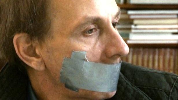 Ein Mann hat Klebeband über dem Mund.