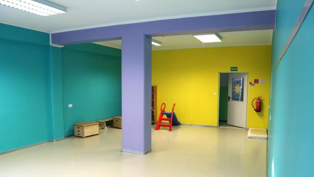 Ein farbenfroher Raum mit türkisfarbenen und gelben Wänden, sowie lila Säulen.