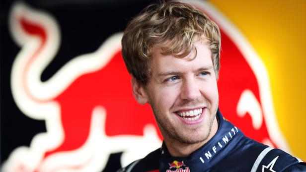 Sebastian Vettel lächelt vor dem Red Bull-Logo.