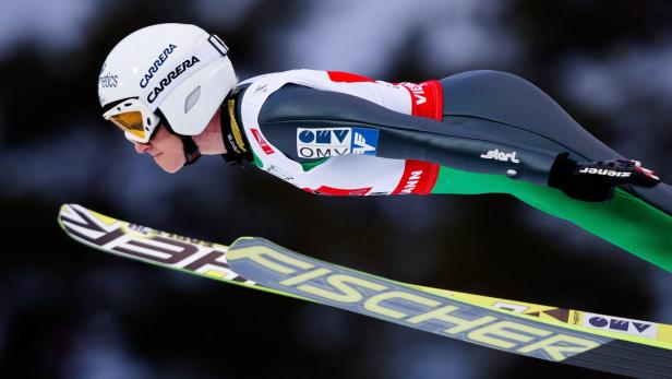 Ein Skispringer in der Luft mit Ski der Marke Fischer.