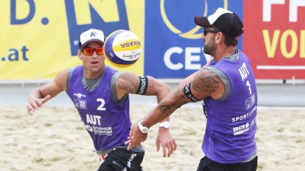 Zwei Beachvolleyballspieler aus Österreich bei einem Spiel im Sand.