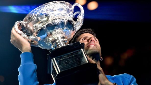 Novak Đoković hält eine Trophäe hoch.