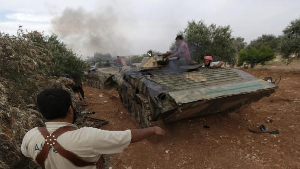 Mehrere Personen befinden sich auf und um zwei Militärfahrzeuge in einer ländlichen Gegend.