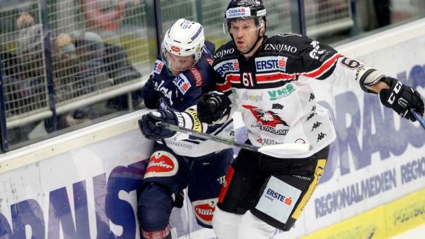 Zwei Eishockeyspieler kämpfen um den Puck am Rande des Spielfelds.