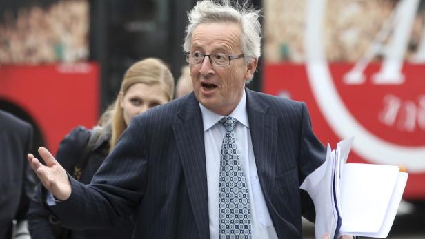Jean-Claude Juncker gestikuliert mit Papieren in der Hand.